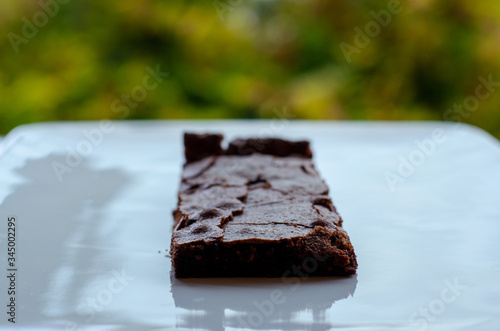 Homemade brownie on white plate. Brownie on black counter. Brownie with decoration. Brownie with smiley.