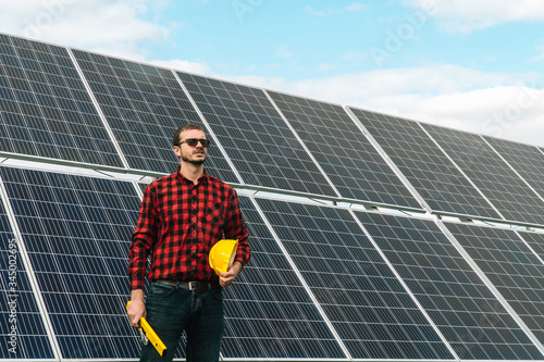 Portrait of a successful young engineer on the background of a solar power station. An engineer checks solar panels
