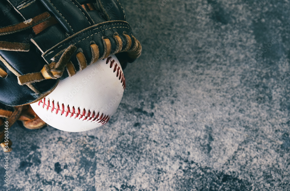 Baseball glove and ball for sport game on blurred texture background.