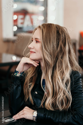 portrait of a blonde girl in a leather jacket sitting in a cafe portrait