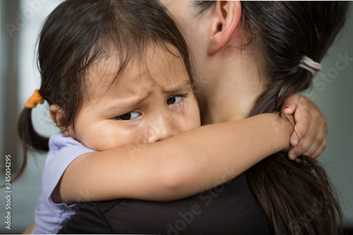 A sad child holding her mother for comfort and safety. photo