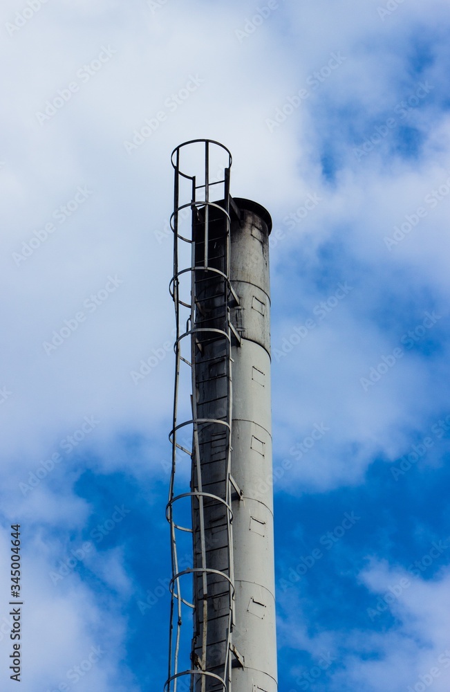 Top of industrial chimney close up. Industrial chimney with utilities. Industrial chimney against sky.