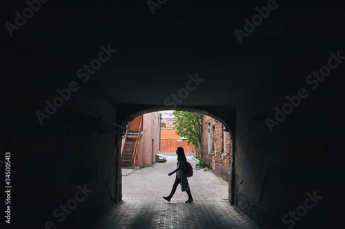 Silhouette of a young girl in an old arch. The concept of walking, loneliness, tourism, slums and poverty.