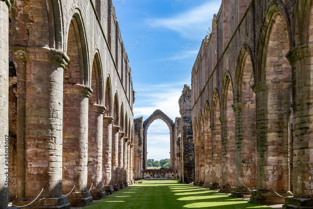 Stone ruins of Fountains Abbey and Studley Royal on a warm, summer day. - obrazy, fototapety, plakaty 