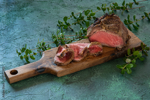  Medium rare roast beef meal with bay leaves on meat fork. Venison, Elk Sirloin Tip Roast. image for menu or cook book