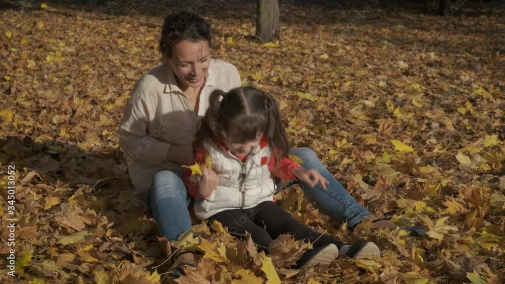 Family in autumn time. Happy little girl with her mom are having fun in the autumn leaves. Family in autumn time. Happy little girl with her mom are having fun in the autumn leaves.