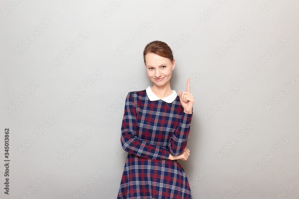 Portrait of happy young woman smiling and pointing up with finger Portrait of happy young woman smiling and pointing up with finger