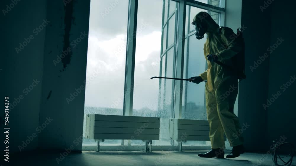 Sanitary worker is pulverizing chemicals onto the window Sanitary worker is pulverizing chemicals onto the window
