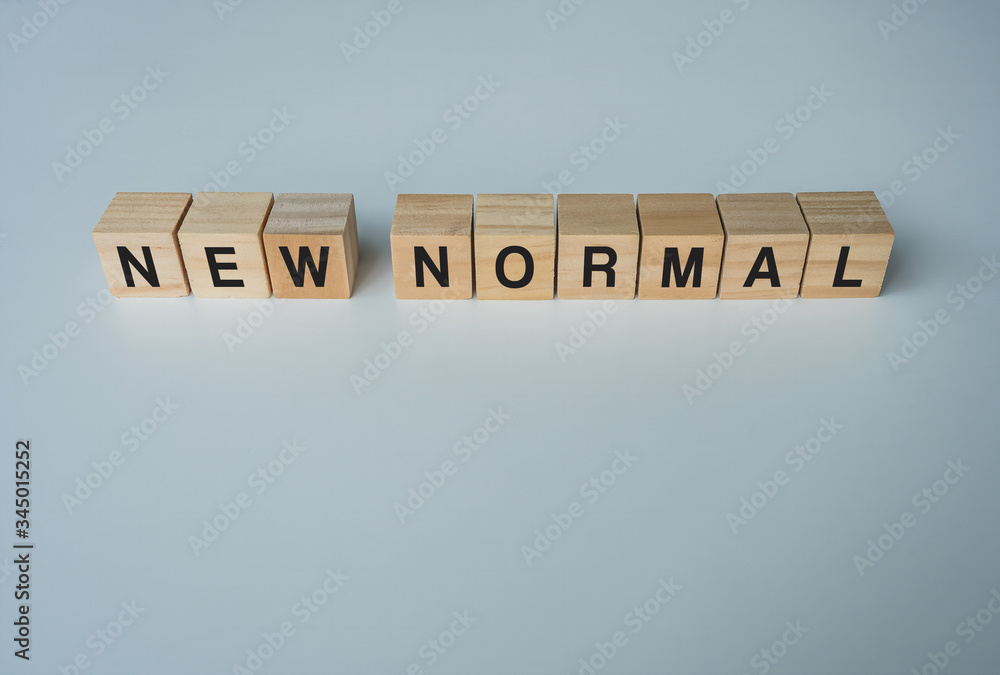 NEW NORMAL word on wooden cube. New normal after covid-19 pandemic with social distancing and good hygiene NEW NORMAL word on wooden cube. New normal after covid-19 pandemic with social distancing and good hygiene