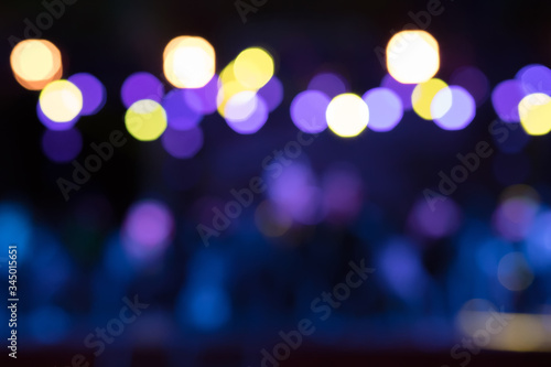 Beautiful blurred background of the nighttime stage show with yellow, purple and blue lights