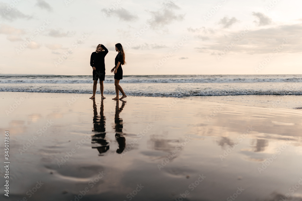 Naklejka premium Attractive man and woman enjoying romantic evening on sunset