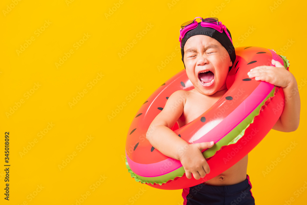 Summer vacation concept, Portrait Asian happy cute little child boy wear goggles and swimsuit hold watermelon inflatable ring, Kid having fun on summer vacation, studio shot isolated yellow background Summer vacation concept, Portrait Asian happy cute little child boy wear goggles and swimsuit hold watermelon inflatable ring, Kid having fun on summer vacation, studio shot isolated yellow background
