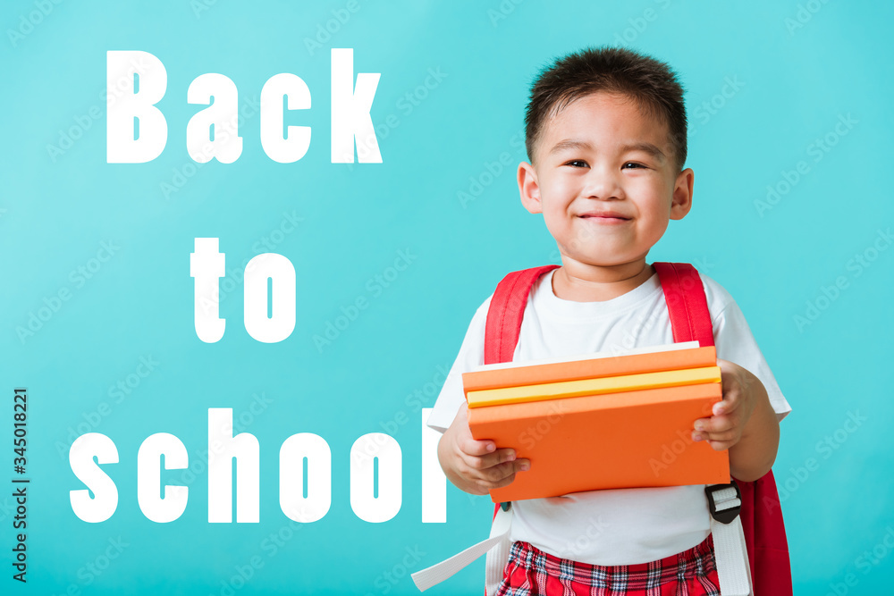 Back to school. Portrait Asian happy funny cute little child boy smiling and laugh holding books, studio shot isolated blue background. Kid from preschool kindergarten with school bag education Back to school. Portrait Asian happy funny cute little child boy smiling and laugh holding books, studio shot isolated blue background. Kid from preschool kindergarten with school bag education