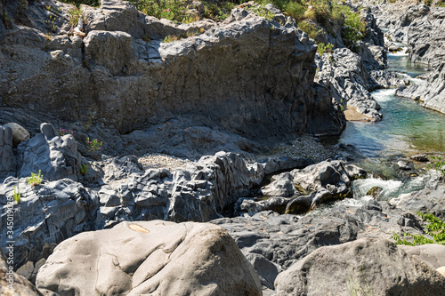 Mountain river with blue water and Volcanic stones around. Gorge of Alcantara on island Sicily in Italy. Beautiful mountain landscape.