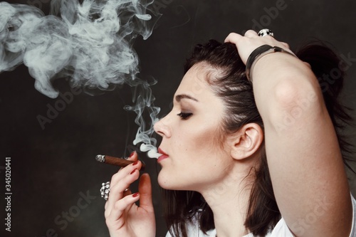 Foto Beautiful european bossy brunette girl smoking a cigarillo like a boss in studio on isolated background