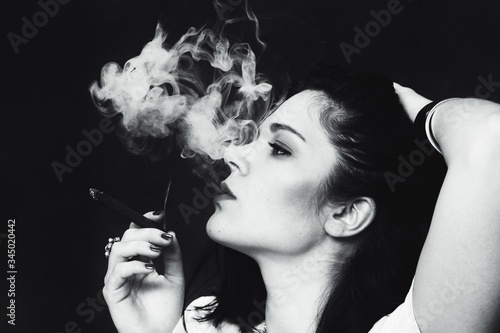 Obraz na płótnie Beautiful european bossy brunette girl smoking a cigarillo like a boss in studio on isolated background