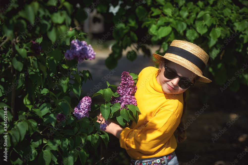 Portrait of a little girl in a straw hat with lilac