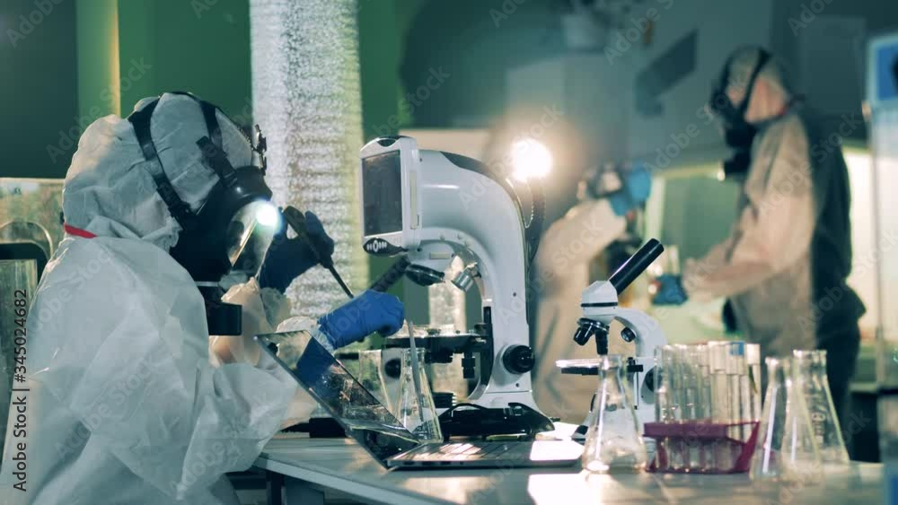 People work with microscopes in laboratory while developing a vaccine. People work with microscopes in laboratory while developing a vaccine.