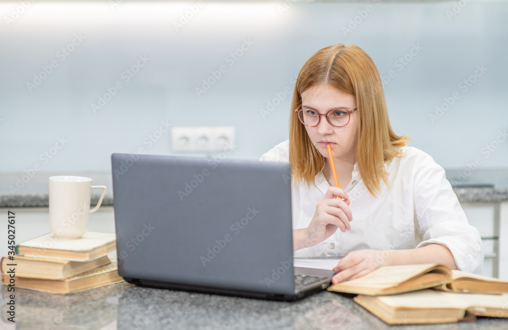 Teen girl doing homework with laptop. Distance learning concept Teen girl doing homework with laptop. Distance learning concept