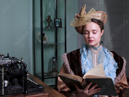 Young woman in blue vintage dress late 19th century reading the book in retro room
