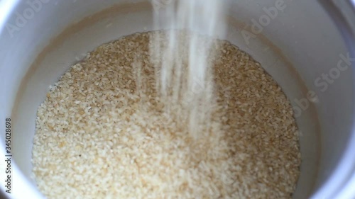 shallow focus raw rice or cereal fall in to silver container.