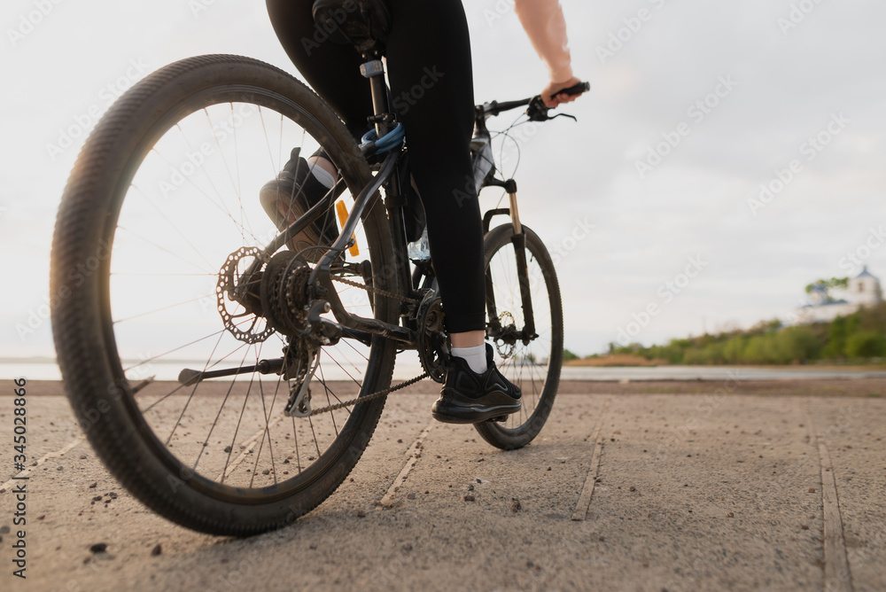 Fototapeta premium Młoda piękna dziewczyna-sportowiec uprawia sport i jeździ na rowerze nad morzem.