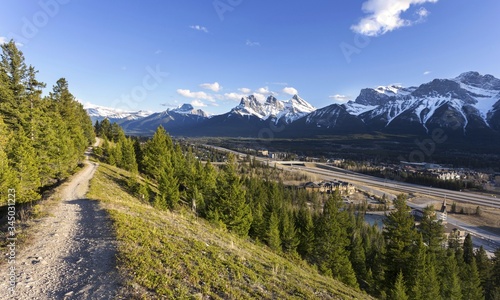 Springtime Landscape Panorama of Bow Valley and City of Canmore with distant Three Sisters Mountain Peak on Horizon. Alberta Foothills of Canadian Rockies