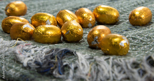Chocolate eggs wrapped in golden paper arranged on green fabric symbolizing Easter Day
