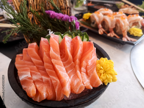 Close up juicy yummy delicious tasty raw and fresh fatty Sliced ​​orange salmon sashimi fish in Japanese style popular seafood in black plate eat with fresh wasabi .
