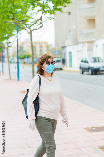 a woman in a protective mask walks outdoors