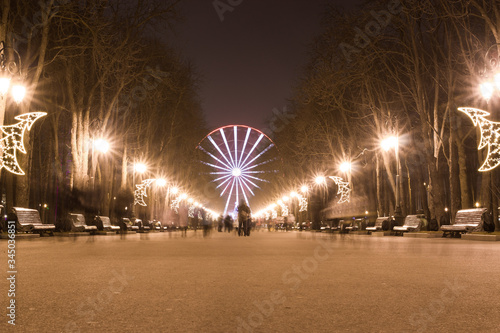 Ferris wheel in a night park. Blurred people walking in the park