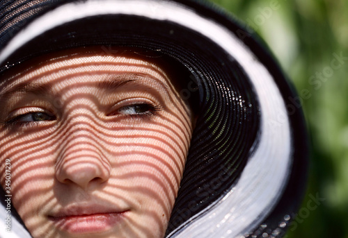 Beautiful girl portrait. Interesting shadows from a hat on a woman's face. Closeup face of a young girl. Horizontal, close-up, cropped shot. Concept of female beauty.
