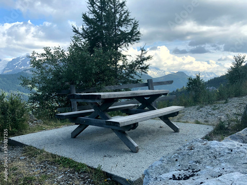 Mountain landscape. Perspective view of the mountains covered with snow. In the foreground are a wooden bench and a handmade table. Horizontal, nobody. The concept of natural beauty and tourism.