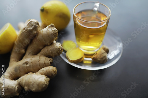 Ginger root whole and sliced. Ginger tea with lemon on the dark background. Fresh ginger root on stone background. Vitamins. Free space for your text. photo