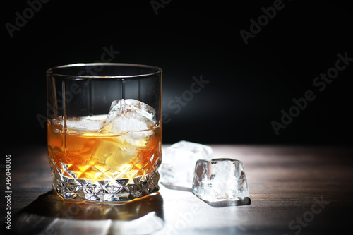 Принти на полотні A glass of strong alcoholic drink with ice on a wooden bar counter