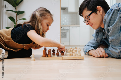 Little girl is enthusiastic about her move, playing chess against her father