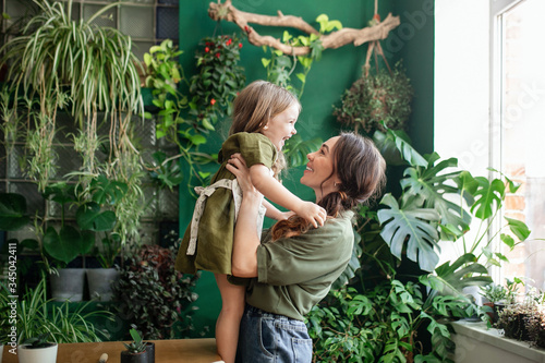 Mother and daughter plant green plants in the greenhouse. 