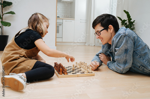 Father and little daughter playing chess on a kitchen floor at home