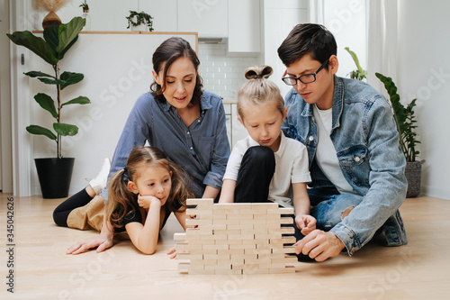 Family playing muscle control and logic game, building things with wooden blocks