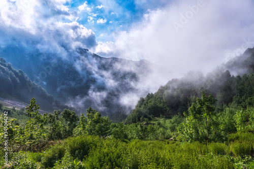Heavy fog and clouds in mountain gorge in the summer or spring. A layer of melting snow in the summer in high mountains.
