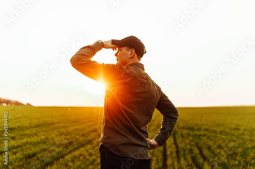 Tableau sur toile Young farmer stands in the green field checking and waiting for harvest to grow