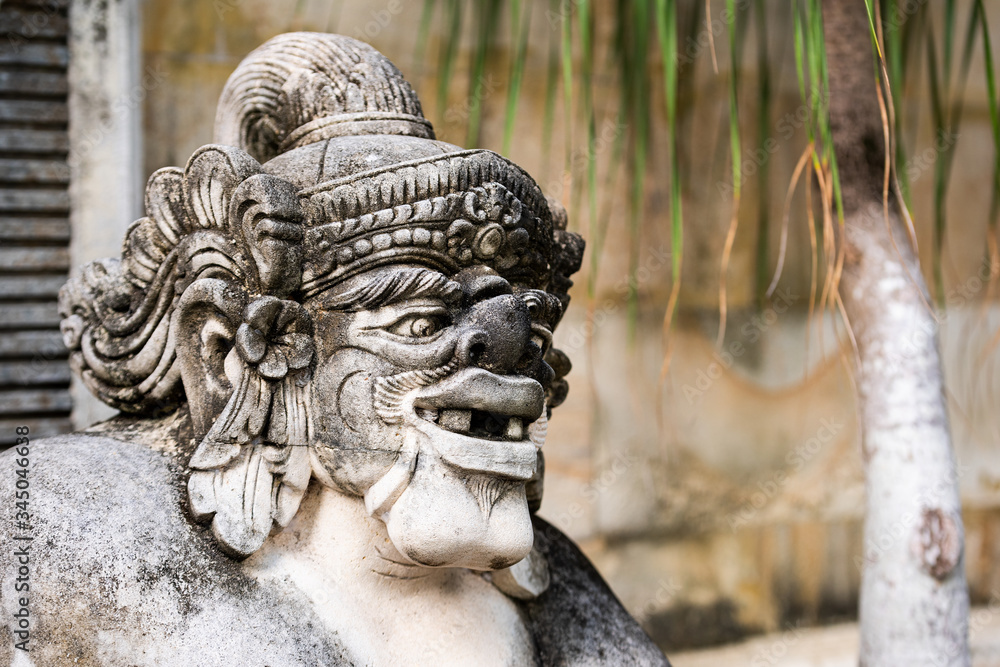 Traditional stone statue in Balinese landscape in soft focus