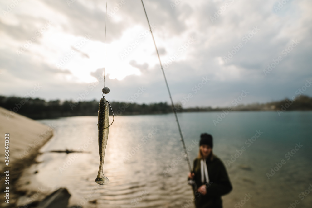 Fisherman with rod throws bait into the water on river bank. Fishing for pike, perch, carp. Background wild nature. The concept of rural getaway. Woman catching a fish on lake or pond with text space.