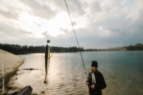 Fisherman with rod throws bait into the water on river bank. Fishing for pike, perch, carp. Background wild nature. The concept of rural getaway. Woman catching a fish on lake or pond with text space.