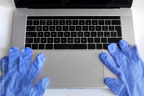 mani con guanti in lattice scrivono su computer portatile m isolato su sfondo bianco