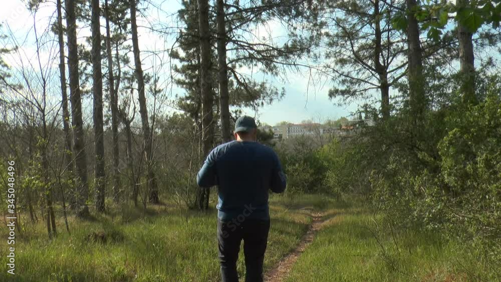 a man in a protective mask and gloves in the forest takes pictures of trees. Concept, a person doesn't feel protected from the coronavirus pandemic anywhere. a man in a protective mask and gloves in the forest takes pictures of trees. Concept, a person doesn't feel protected from the coronavirus pandemic anywhere.