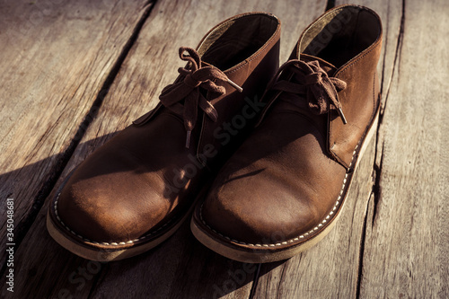 Brown stylish boots on wood background, retro color