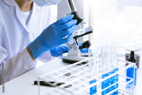 Young Asian scientist Working looking through a microscope doing research for analyzing a Experiments sample in a forensic laboratory.