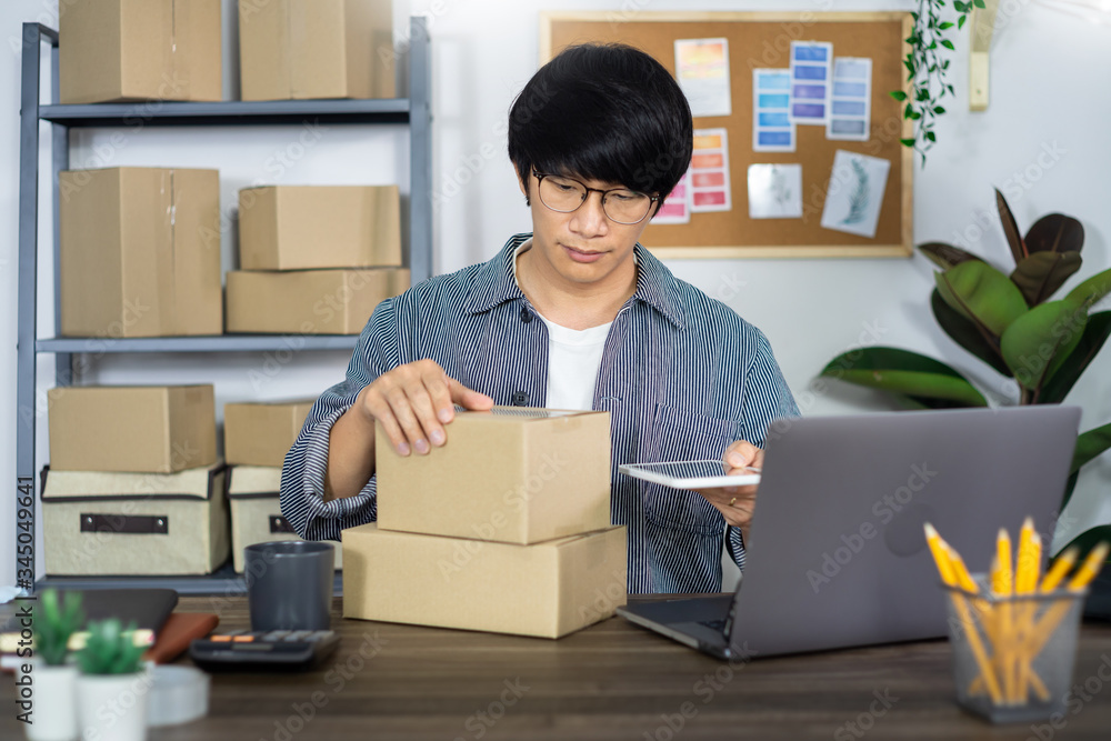 Asian business man startup SME entrepreneur or freelance working in a cardboard box prepares delivery box for customer, Online selling, e-commerce, packaging and shipping concept. Asian business man startup SME entrepreneur or freelance working in a cardboard box prepares delivery box for customer, Online selling, e-commerce, packaging and shipping concept.