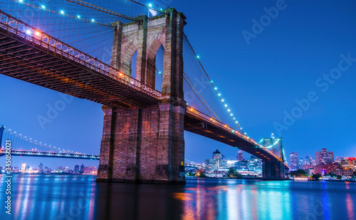 beautiful brooklyn bridge at night with reflection in water.